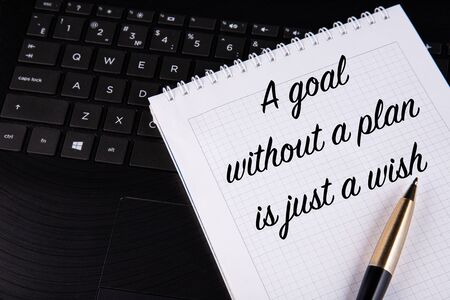 A goal without a plan is just a wish - written on a notebook with a pen.