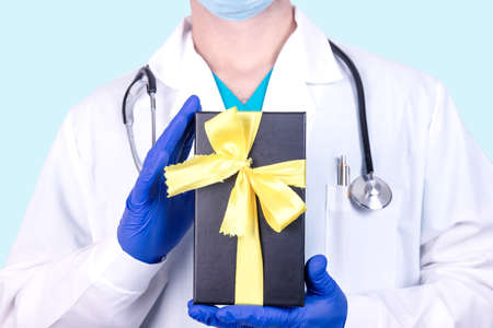 Bad news medical concept. Doctor holds a black box tied with a yellow ribbon.の写真素材
