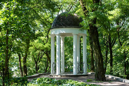 Summer landscape, sunny morning in the old park with a summer arbor of white color with columns. Manor park.の写真素材