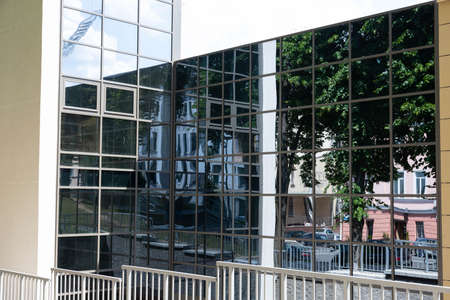 Glass building. A modern detail of an office building, trees are reflected from the glass surface of...