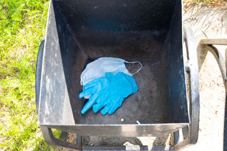 Thrown away medical gloves and protective masks in the trash bin after quarantine. Recycling and...