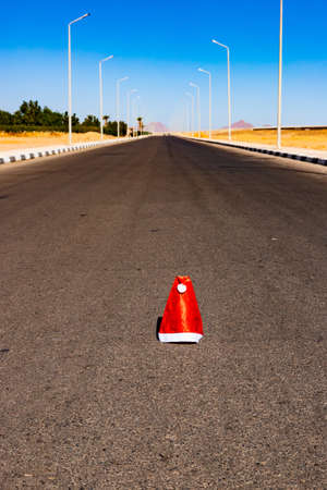 The beginning or end of the Christmas holidays, a lost or thrown Santa hat lies on the highway....