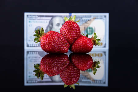 Red strawberries on a background of one hundred US dollars. Business concept. Sale of strawberries. Sweet life. Selective focusの写真素材
