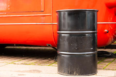 One black barrel against a red van is used as a table. Art.の写真素材