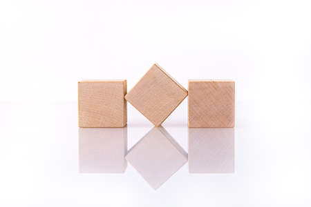 Three wooden cubes, blocks lie on a white reflective surface. Concept for writing a word of three letters. Business idea.の写真素材