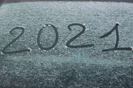 Number 2021 written on the snowy glass of a car. New Year concept on a white background. Banner.の写真素材