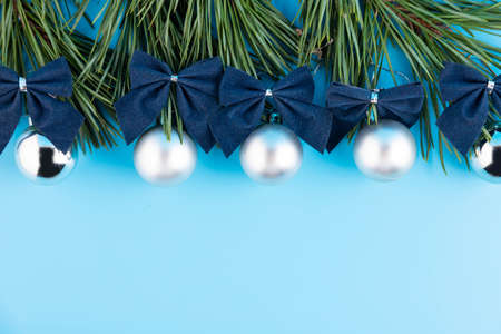 The Christmas tree branch is decorated with silver balls on a blue background.の写真素材