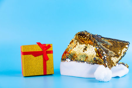 Creative Christmas composition. Greeting card, invitation or flyer. Golden hat of Santa Claus and New Year's toys on a blue background.の写真素材