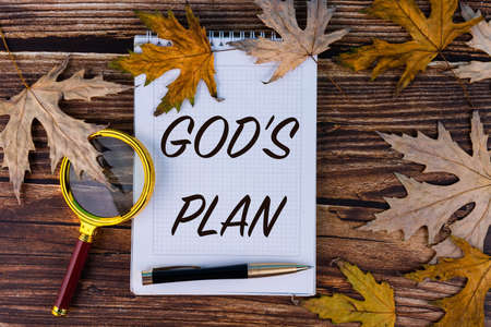 God's plan, the text is written in a white notebook with a pen on a background of autumn, maple...