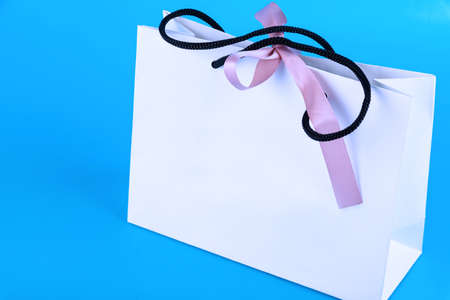 Blank craft bag mockup, mockup of white paper shopping bag with handles on blue background ..の写真素材