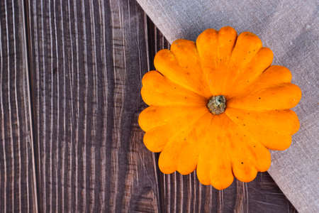 Fresh yellow pumpkin, medium size, on linen, on a wooden surface. Copy space.の写真素材