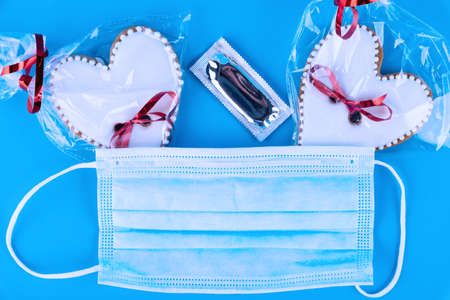 Valentine's day gift, erotic gadget, condom, heart-shaped cookies and medical mask on a blue...
