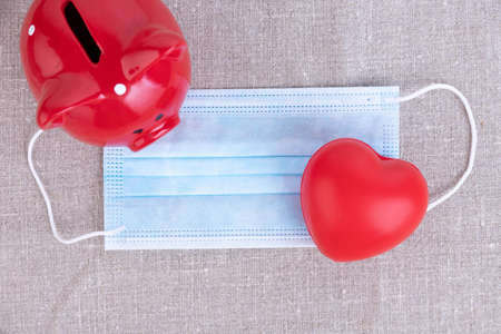 Disposable medical mask, red heart, piggy bank. Medical conceptの写真素材
