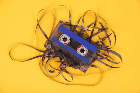 Old cassette tape with unwound tape on a yellow background.の写真素材