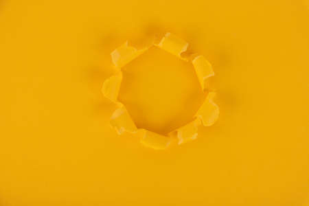 A yellow sheet of paper with a hole in the middle. Background, texture. Copy space.の写真素材