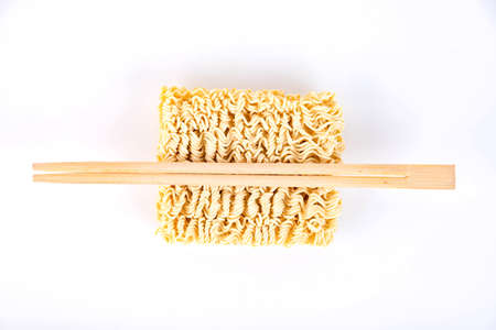 Yellow instant dry noodles with wooden chopsticks. Texture, background.の写真素材