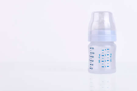 Baby bottle with pacifier and milk for feeding milk on a light background. Copy space.