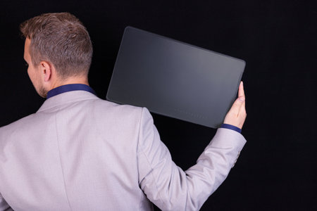 A businessman is working on his digital tablet on a black background. Business concept, idea.