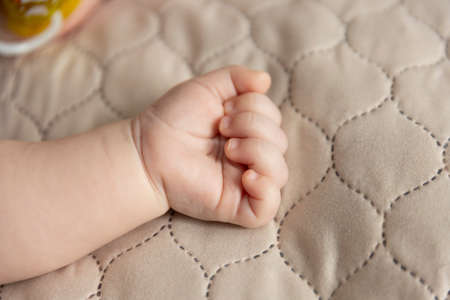 Hand of a baby lying on the bed. Close-up of the palm. Fatherhood and children's day concept.