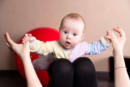 The child plays, does exercises, does gymnastics with his mother at home.の写真素材