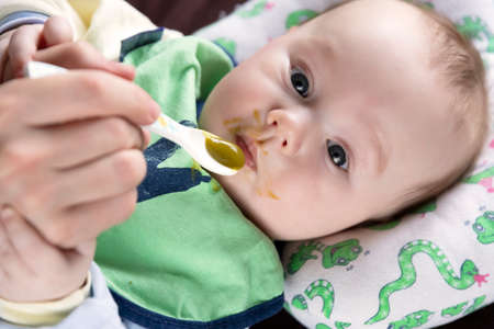 The child, feeding from the first spoon, tastes vegetables for the first time, emotions.の写真素材