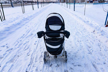 The child sleeps in a stroller in the winter. The concept of winter walks with children in the fresh air.の写真素材