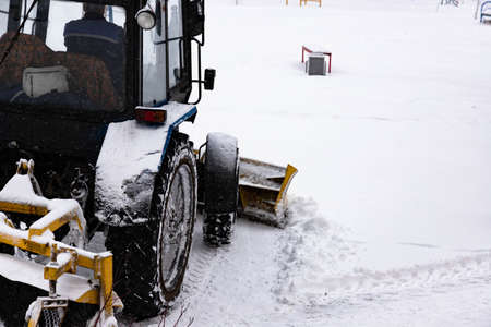 The tractor clears the road from snow in winter during a snowfall.の写真素材