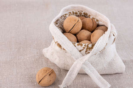 Organic fresh harvested walnuts in burlap on gray linen background. Copy spaceの写真素材