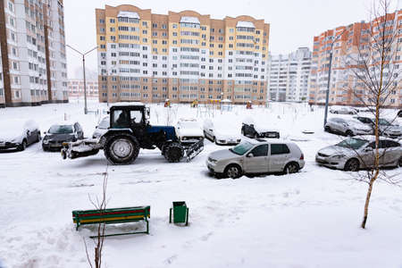 The tractor clears the road from snow in winter during a snowfall.の写真素材