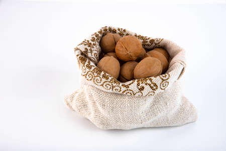 Organic fresh harvested walnuts in burlap sack on white background Copy spaceの写真素材