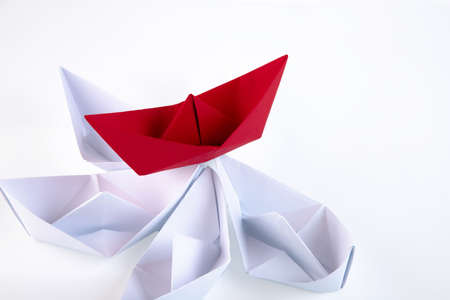 one red paper boat between many white paper boats. Copy space.の写真素材