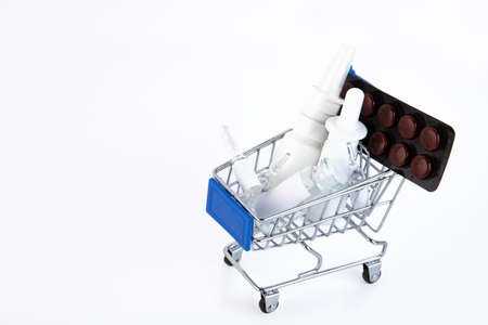 Variety of pills in blister packs in a mini shopping trolley on a white background. Health and medicine concept. Concept of online shopping in a pharmacy. Copy space.の写真素材