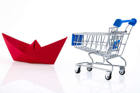 Shopping cart, e-commerce, digital commerce, retail, red paper boat, white background. Copy space.の写真素材