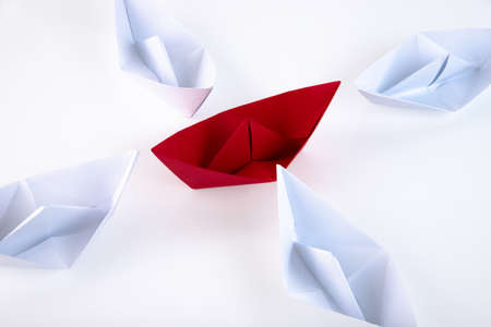 one red paper boat between many white paper boats. Copy space.の写真素材