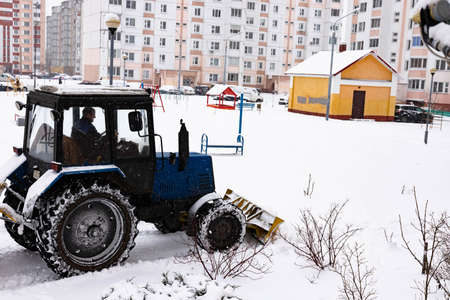 The tractor clears the road from snow in winter during a snowfall.のeditorial素材
