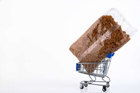 Buckwheat, groats in a plastic bag, in a mini shopping trolley, shopping cart, isolated on a white...