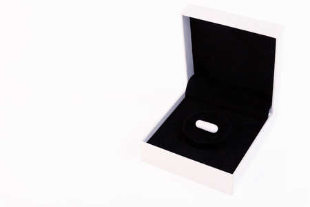 White gift box with black velvet and pill, capsule inside, on a white background. Copy space.の写真素材