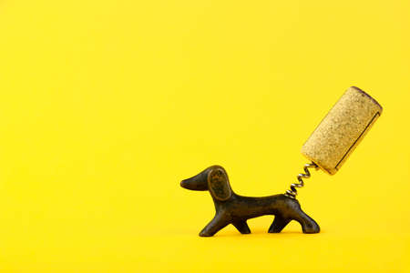 Close-up of a corkscrew in the form of a dachshund dog with a wine cork in the form of a tail On a yellow background. Copy space.の写真素材