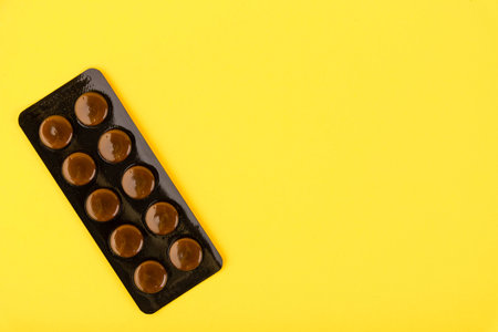 Blister pack of brown medical pills on a yellow background. Copy space.