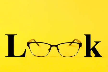 Glasses, text Look, on a yellow background. Copy spaceの写真素材