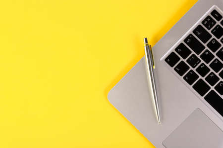 Leptop, notebook, pen, on a yellow background. Flat lay. Copy space.