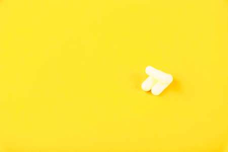 White capsules, tablets on a yellow background. Copy spaceの写真素材