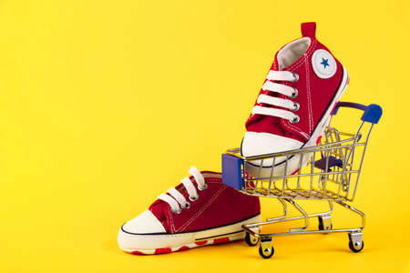 A pair of red sneakers in a trolley on a yellow background. Online shopping. electronic commerce. Copy space.の写真素材