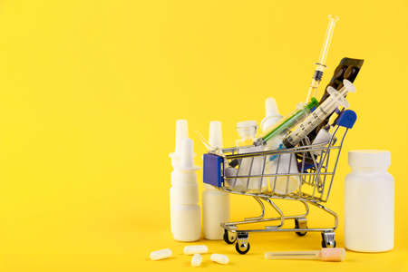 Basket with pills, syringe, spray. Online pharmacies. Yellow background. Stay at home concept. Copy spaceの写真素材