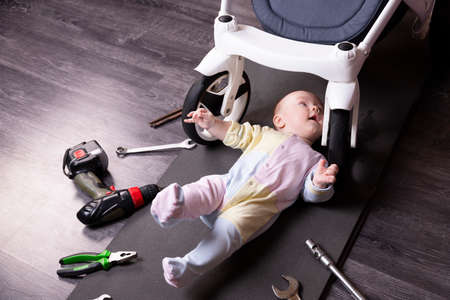Boy mechanic repairs the suspension of a baby carriage. We repair everything that travels. Humor, challenge.の写真素材