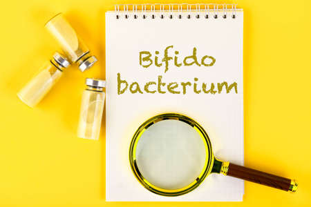 Vials, ampoules with dry probiotic, bifidobacteria, with probiotic powder inside on a yellow...