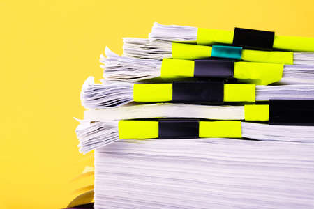 Piles of white papers work large piles of papers stacked together. On the desk in the office with black clip. Documents that are not finished. Business concept.の写真素材