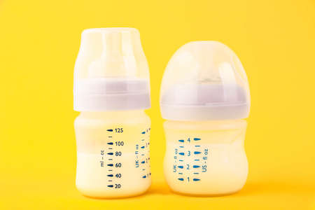 White plastic baby bottle with pacifier, rich in baby food, on yellow background. Copy space.の写真素材