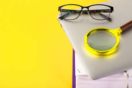 Office, folder with documents awaiting verification, magnifying glass, on a yellow background....