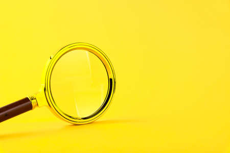 Magnifying glass in a gold frame on a yellow background. Copy space.の写真素材